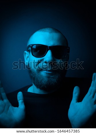 Studio portrait of a charismatic guy in neon style. Stock photo of a bearded guy surprised by surprise.