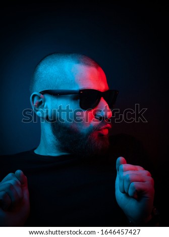 Studio portrait of a charismatic guy in neon style. Stock photo of a bearded guy surprised by surprise.