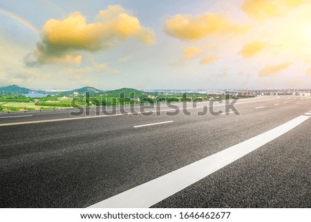 Wide asphalt highway and city suburb skyline in Shanghai at sunset.