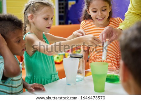 Kids doing chemical experiment at entertainment center. Flasks with colorful liquid on table. Childrens party entertainment.
