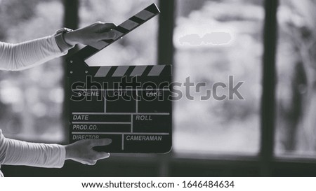 A movie production clapper board. Hands with a movie clapperboard on grey background with copy space, close-up