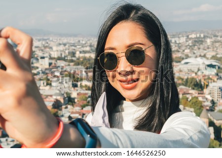 Asian woman tourist is taking selfie of herself with landscape view of Tbilisi city from the moutain in Georgia.
