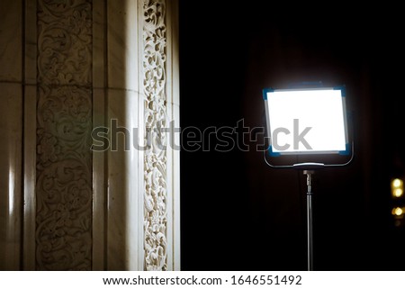 Powerful studio light near a white marble column with a dark background