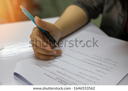 Hand holding a pencil working on writing test, picture of hand in selective focused mode holding a pencil while reading test quiz, education or academic concept image of student in the training room