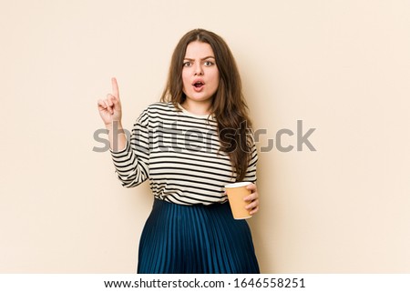 Young curvy woman holding a coffee having some great idea, concept of creativity.