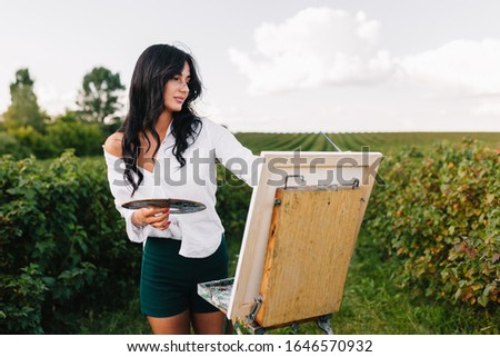 Beautiful girl drawing in the field