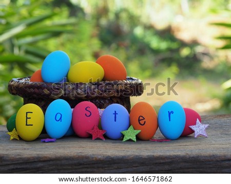 Colorful eggs write Easter words at horizontal row and paper star on the wood table and nature background.