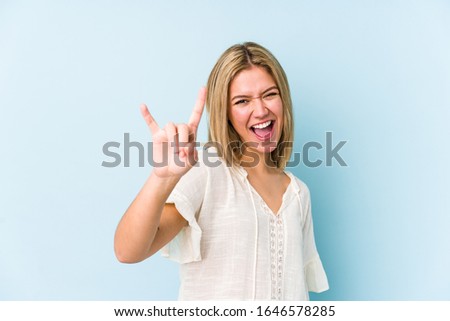 Young blonde caucasian woman isolated showing a horns gesture as a revolution concept.