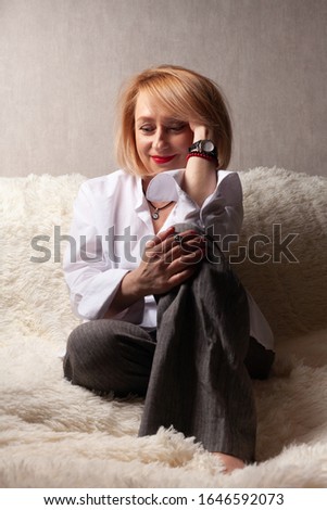 Portrait of an attractive middle-aged woman. Homemade portrait on the couch, middle-aged blonde.