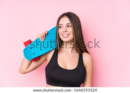 Young caucasian skater woman isolated on pink background