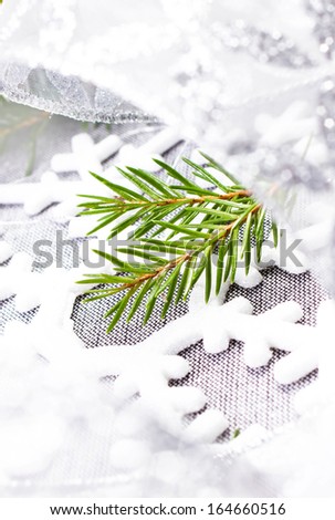 Christmas tree branch and silver ribbon close up. White Christmas ornaments on soft grey background. Christmas Time.
