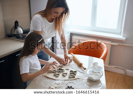 young cheerful mother and her child spending time in the kitchen, close up side view photo, friendship, relation between parents and children