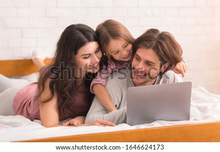 Happy Family With Little Daugher Using Laptop In Bed, Watching Movies And Cartoons, Spending Time At Home Together, Selective Focus