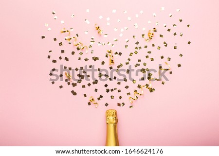 Bottle of champagne and confetti on pink background, top view. Concept holiday, celebrate, Saint Valentine's Day, birthday.