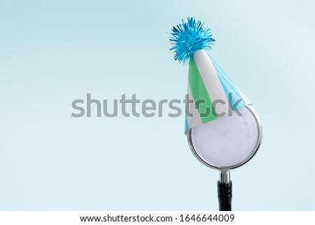 Doctor's day and World health day concept. Medical stethoscope in a festive cap on light blue background. Creative medical background, postcard. Copy space, close up
