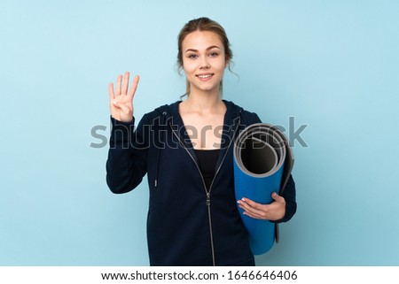 Teenager Russian girl holding mat isolated on blue background happy and counting four with fingers