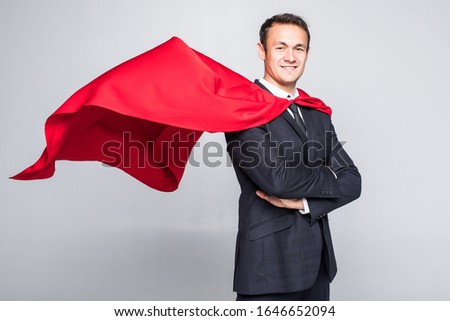 A businessman in a hero red cape and a mask in front view looking in the distance over his shoulder on white background. Business and success. Planning and analyzing. Past mistakes.