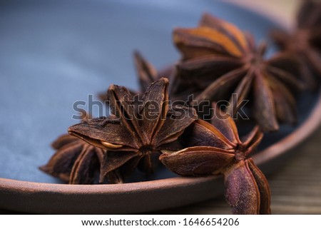 star anise with and without seeds, in a clay plate on a light wooden surface. spice for cooking, medicine, cosmetics. fragrant seasoning. Nice picture. background. decor.
