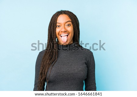 Young african american woman isolated on blue background funny and friendly sticking out tongue.