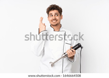 Man using hand blender isolated on white background with fingers crossing
