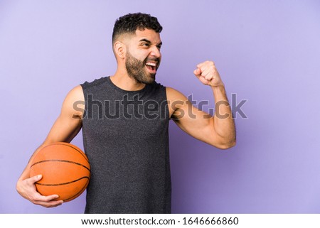 Young latin man playing basket isolated raising fist after a victory, winner concept.