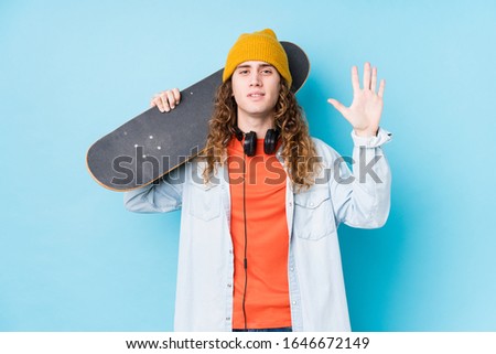 Young caucasian skater man isolated smiling cheerful showing number five with fingers.