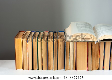 Open hardback book, diary, fanned pages on stack of books on white table in library. Books stacking. Back to school concept. Copy Space. Education learning background