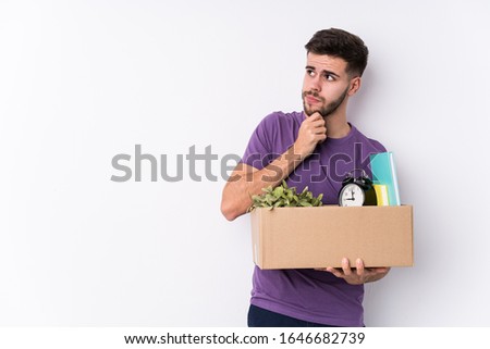 Young caucasian man moving a new home isolated looking sideways with doubtful and skeptical expression.