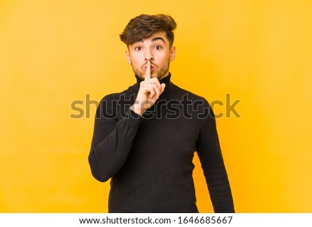 Young arabian man isolated on a yellow background keeping a secret or asking for silence.