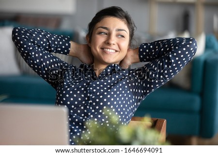 Happy Indian millennial girl distracted from computer work look in window distance dreaming, smiling ethnic young woman lost in thoughts thinking or visualizing, planning future career success Royalty-Free Stock Photo #1646694091