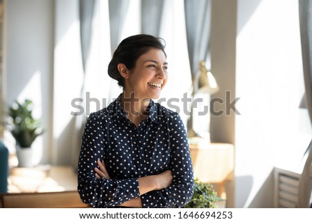 Smiling young Indian woman stand look in distance window dreaming or visualizing, happy overjoyed millennial ethnic girl thinking or planning of future success opportunities at home Royalty-Free Stock Photo #1646694253
