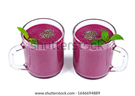 Two glasses of homemade blueberries smoothie and fresh mint leaf isolated on white background