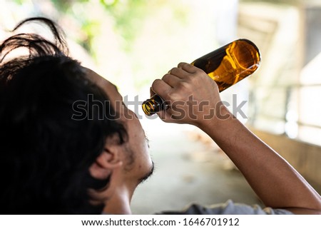 Portrait A drunken man is picking up a bottle to drink.