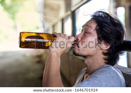 portrait A drunken man is picking up a bottle to drink.