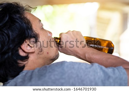portrait A drunken man is picking up a bottle to drink.