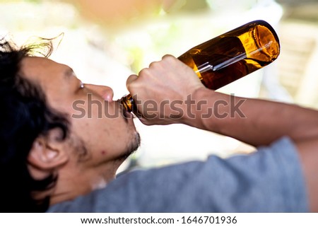 Portrait A drunken man is picking up a bottle to drink.