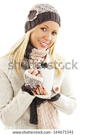 Pretty smiling girl in winter clothes with a white cup of hot drink. Could be coffee, cappuccino, chocolate, tea. 