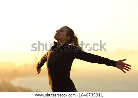 Happy runner breathing fresh air outstretching arms at sunset in the city outskirts Royalty-Free Stock Photo #1646735311