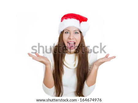 Closeup portrait of shocked, surprised beautiful young woman wearing red santa claus hat, hands in air, mouth eyes wide open, isolated on white background. Positive human emotions facial expressions