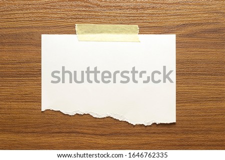 Blank torn paper frame glued with adhesive tape to wooden textured wall as template for graphic designers presentations, portfolios etc.