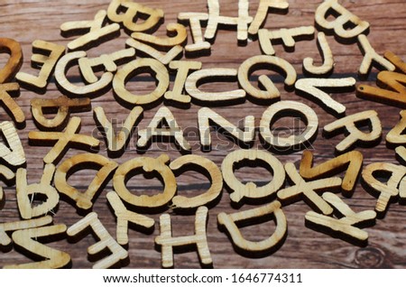 Collection of several letters made of brownish yellow wood against a dark brown background