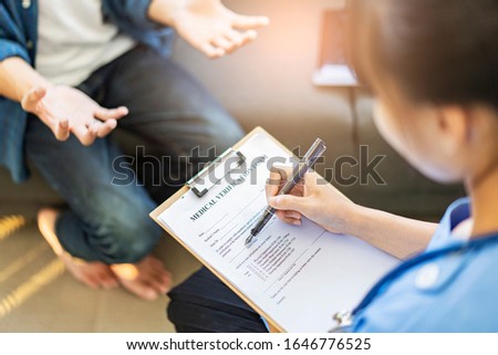 Close up female doctor writing and filling out forms on patient’s diagnosis information, with patient’s hands gesturing frustration on health issues and problem, with doctor holding clipboard and pen