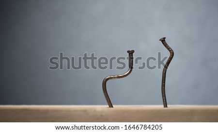 Two bent nails driven into a board. Concept stoop, sciatica and degenerative disc disease - image Royalty-Free Stock Photo #1646784205