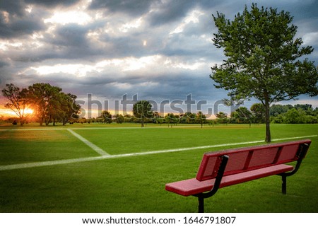Outdoor Soccer European football sports field during sunrise with a red bench and beautiful clouds