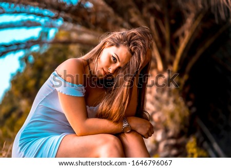 Lifestyle, a serious young woman in a white dress on a palm tree in summer
