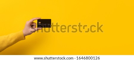 bank card in hand over yellow background, panoramic mock-up Royalty-Free Stock Photo #1646800126
