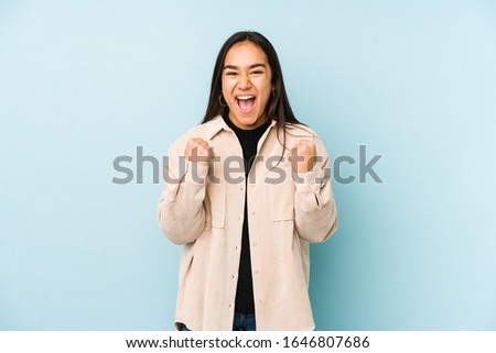 Young woman isolated on a blue background cheering carefree and excited. Victory concept.