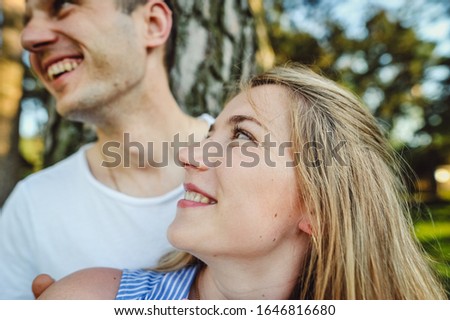 Happy portrait of loving man and woman on background of grass and green trees. Young boyfriend hugging his beautiful girl. Family vacation concept. Love Story.