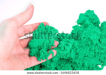 Green sand in hand isolated on a white background. Colored sand for modeling for children