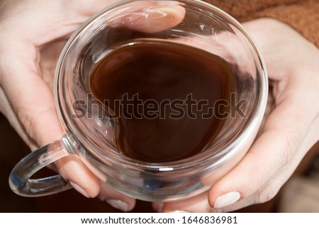 Glass cup in the shape of a heart and double glass in female hands. A cup of coffee.